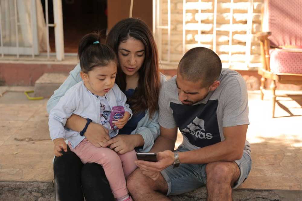 Foto de una familia, dos personas adultas y una niña de 4 años