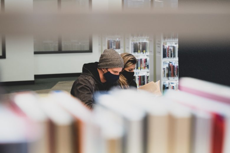 Foto de dos estudiantes leyendo en una biblioteca