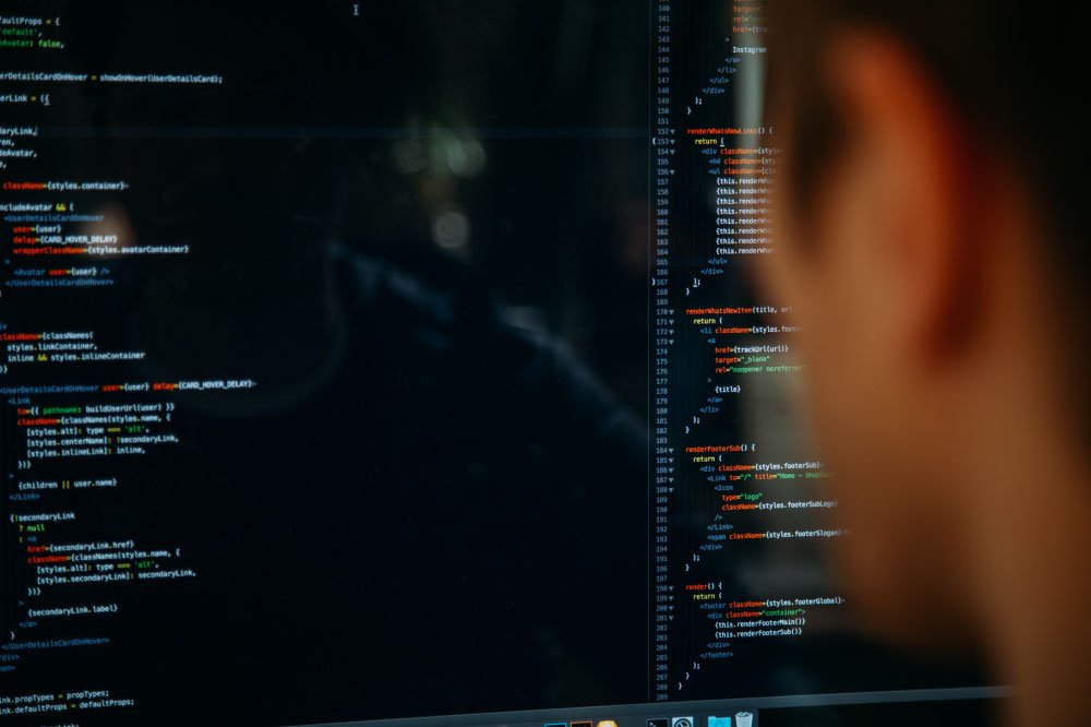 Foto de persona mirando la pantalla de un computador con códigos