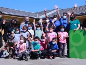 Foto de personas levantando las manos en una actividad con niños y niñas