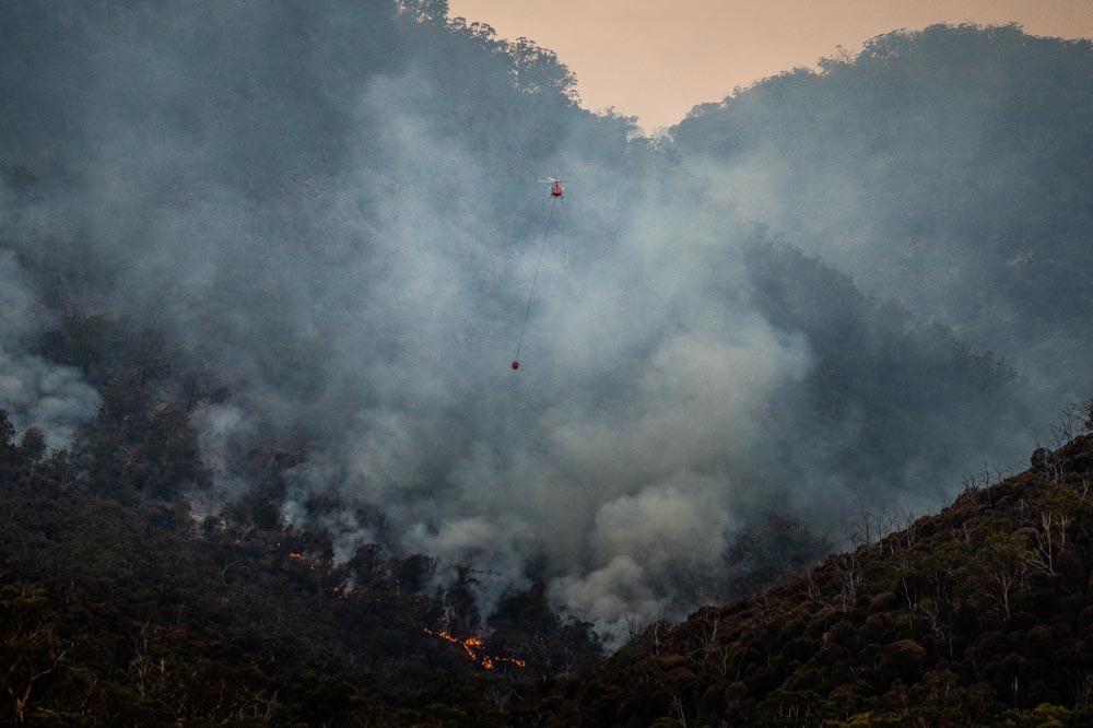 Foto de helicóptero depositando agua en incendio forestal