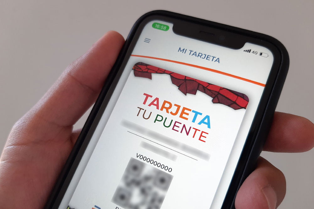 Foto de persona utilizando teléfono móvil con aplicación "Tu Puente"